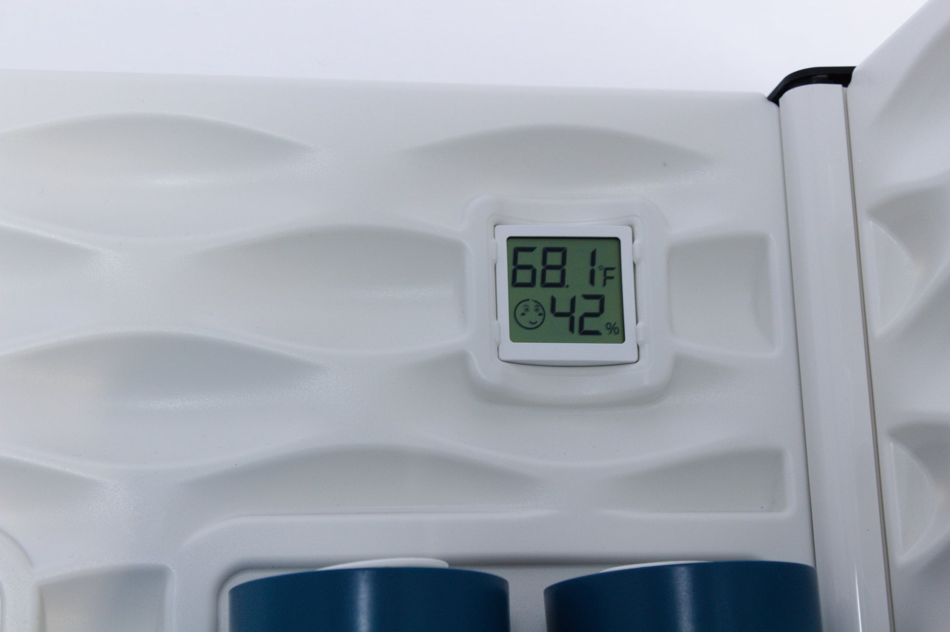 Digital thermometer on a white background with blue cups below.