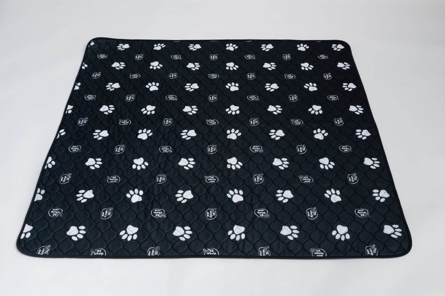 Black quilted pet mat with white paw prints on a white background