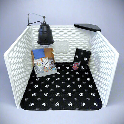 Pet playpen with a black paw print mat, books, and a lamp on a gray background