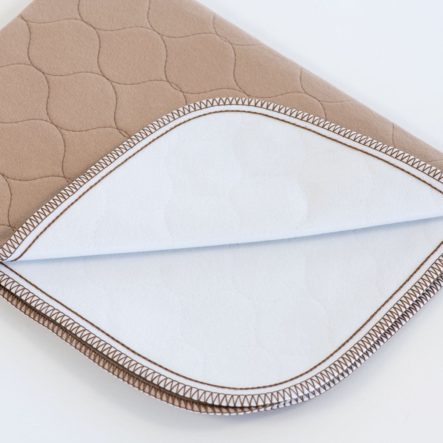 Close-up of a quilted fabric with brown border on a white background