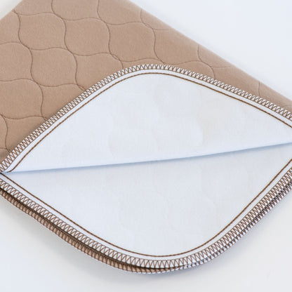 Close-up of a quilted fabric with brown border on a white background