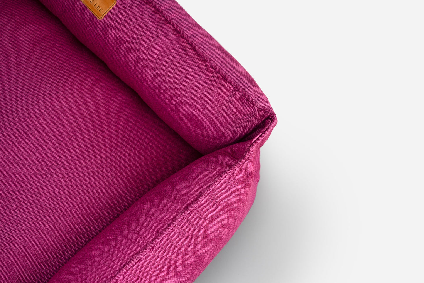 Close-up of a magenta fabric with a visible brand label on a light gray background
