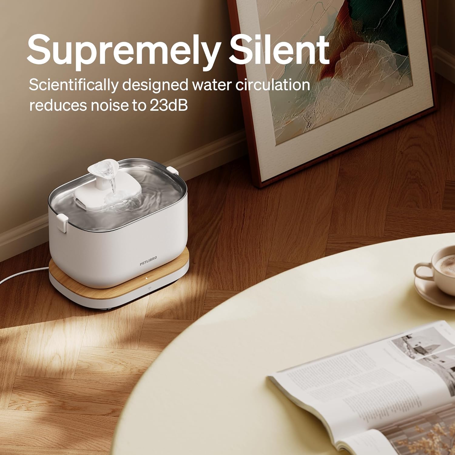 White and wooden pet water fountain on a wooden floor with a cup and saucer in the background.