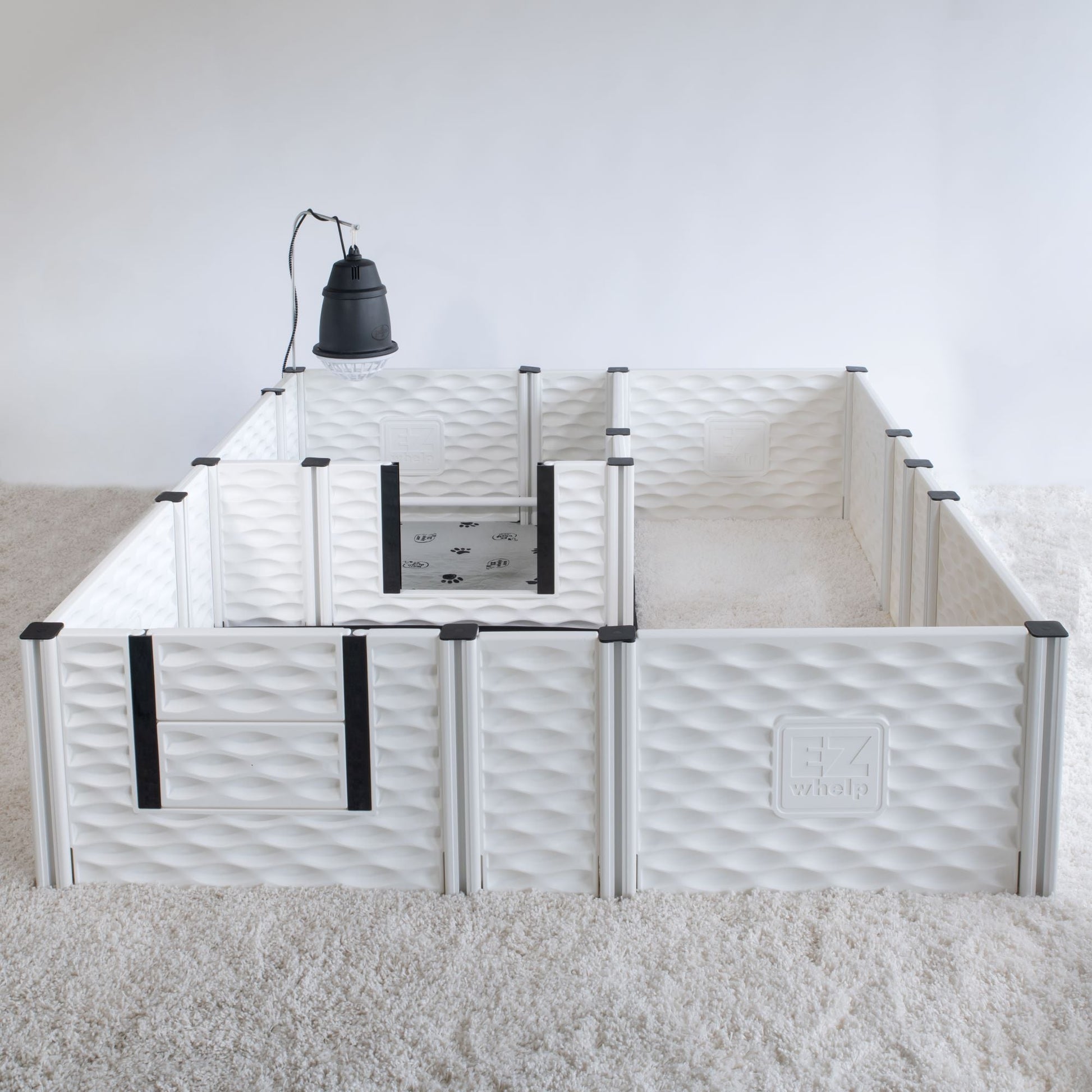 White pet playpen with black accents on a carpeted floor.