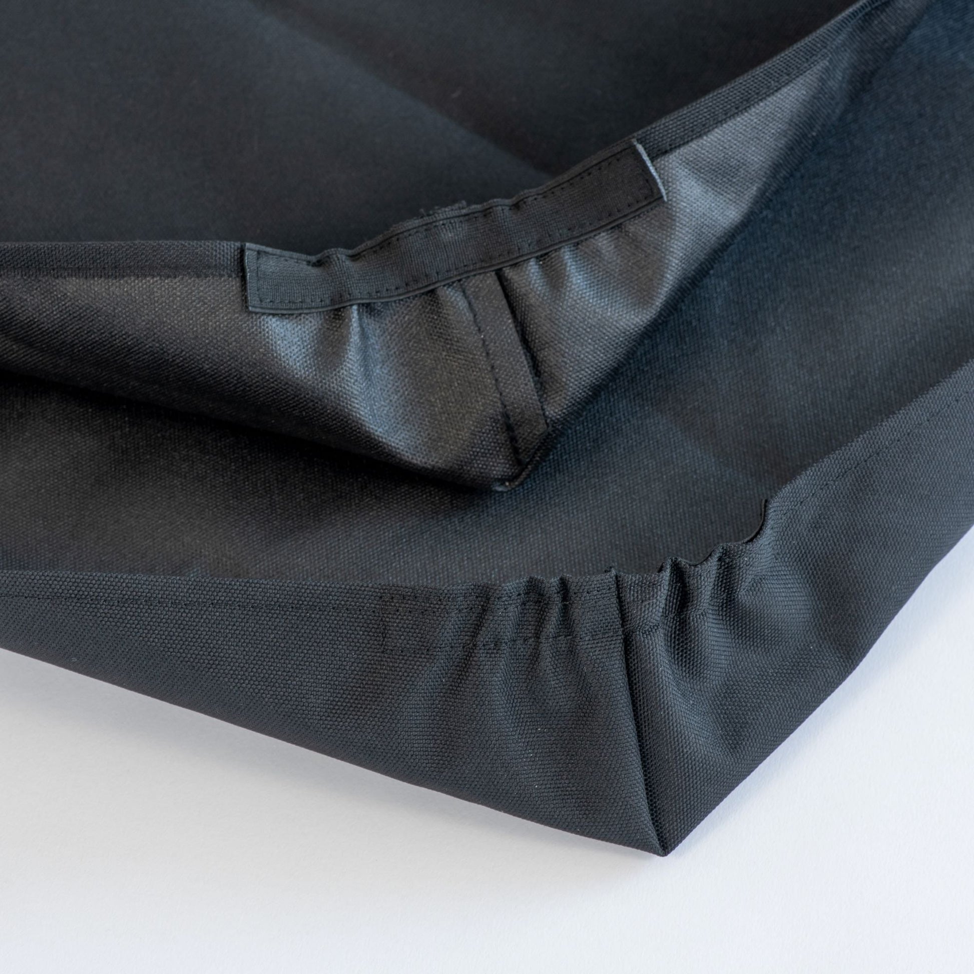 Black fabric with pleated detailing on a white background