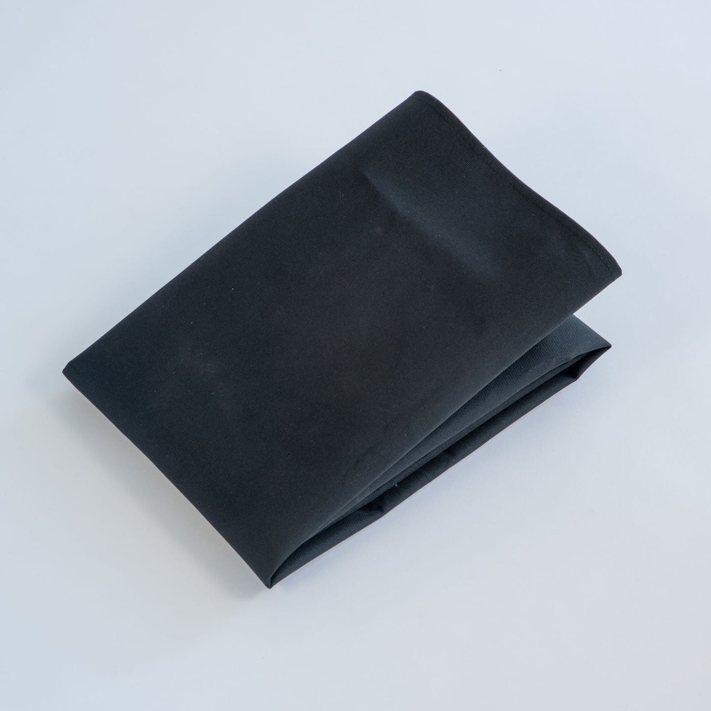 Folded black fabric on a light gray background