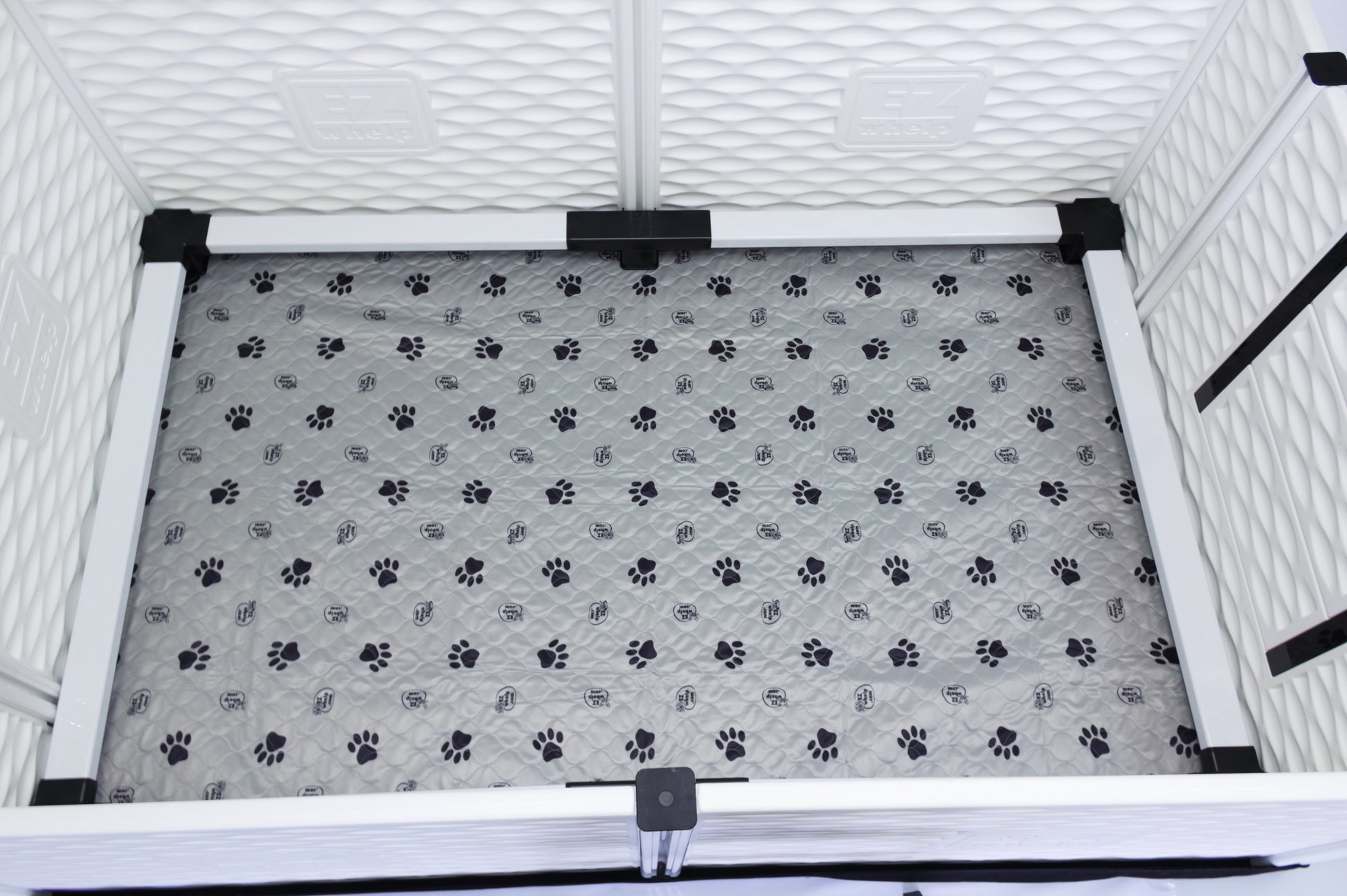 Pet crate with a gray mat featuring black paw prints inside