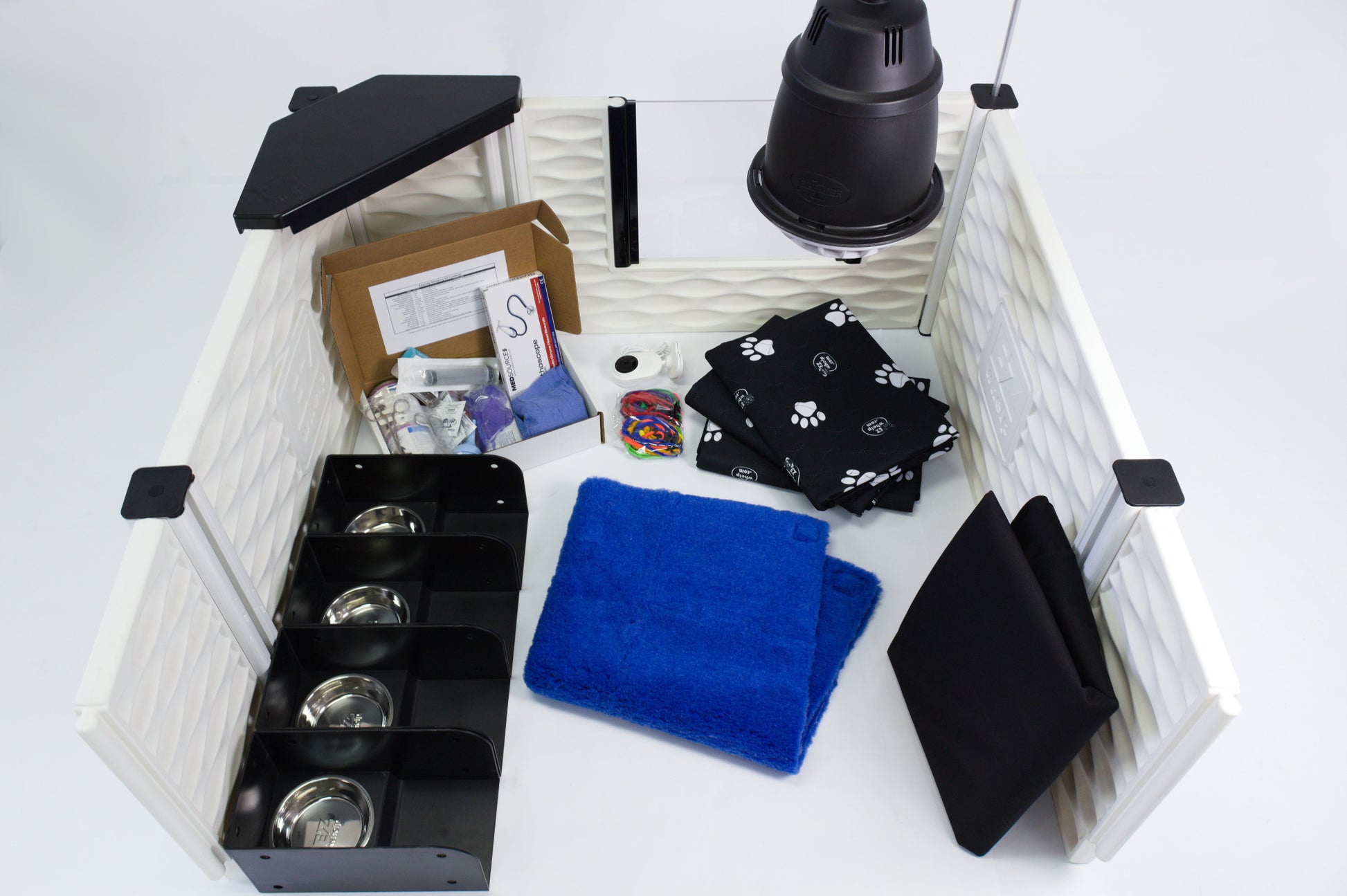 Pet care kit with various items including a blue towel, black bags, and a black lamp on a white surface.