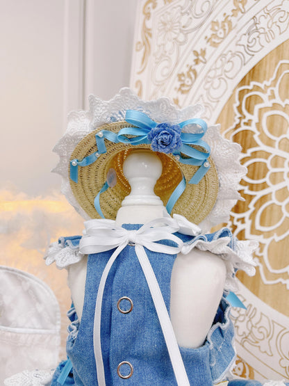 Mannequin wearing a blue dress with a straw hat and floral decorations against a decorative background.