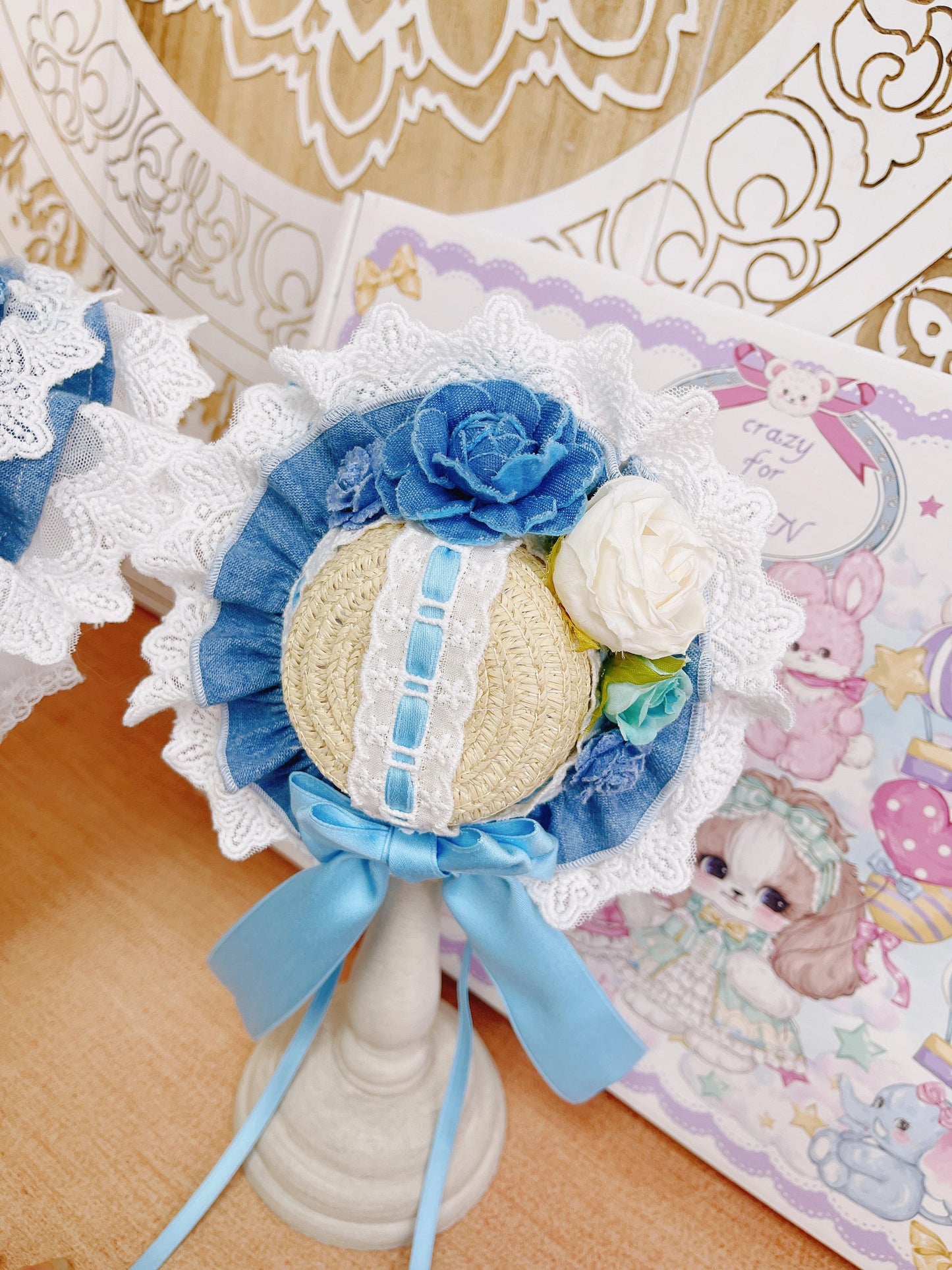 Decorative item with blue and white flowers on a stand, with a pastel-themed background.