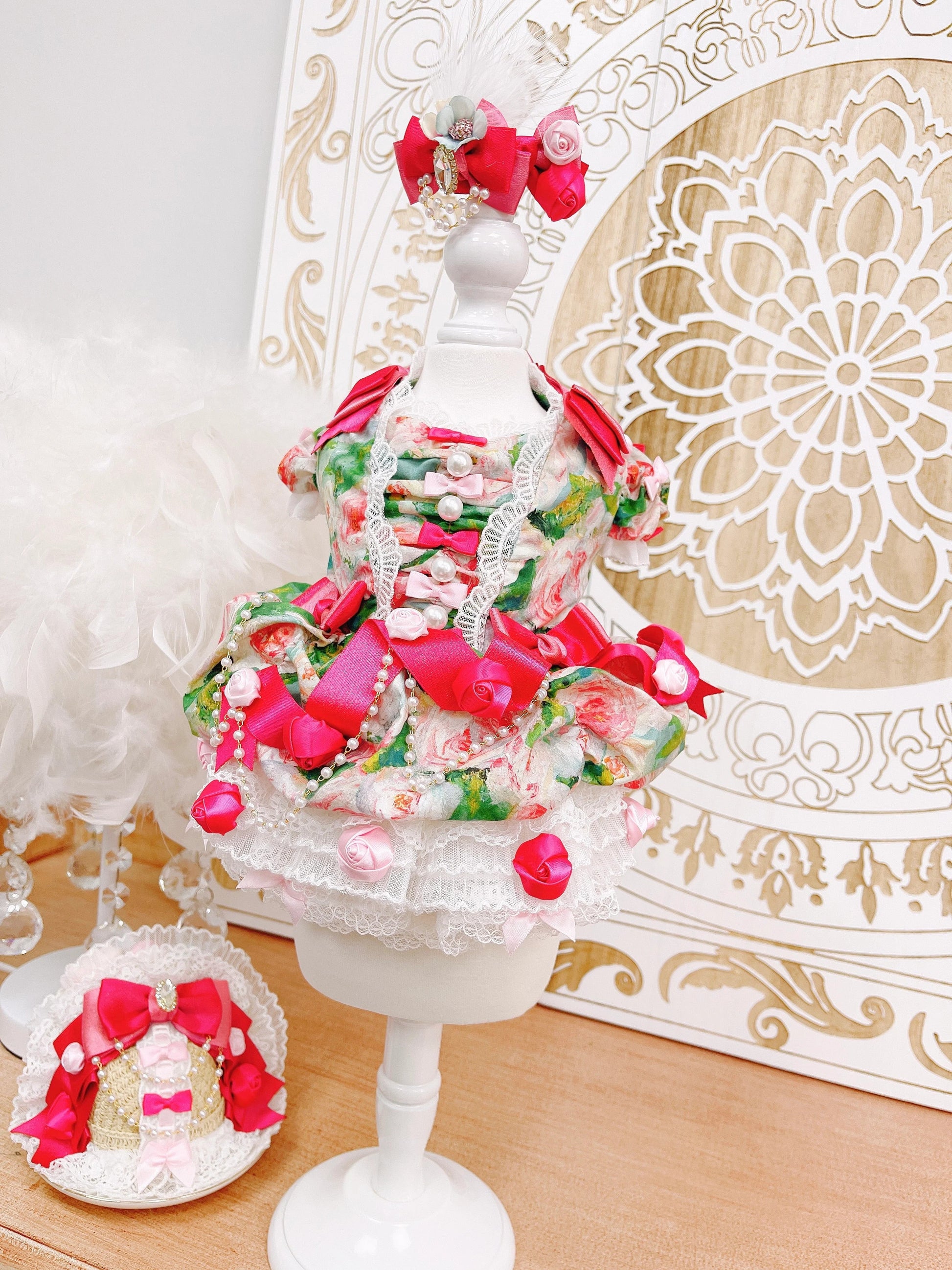 Decorative cake with pink and red accents on a white stand against a decorative white and gold background.