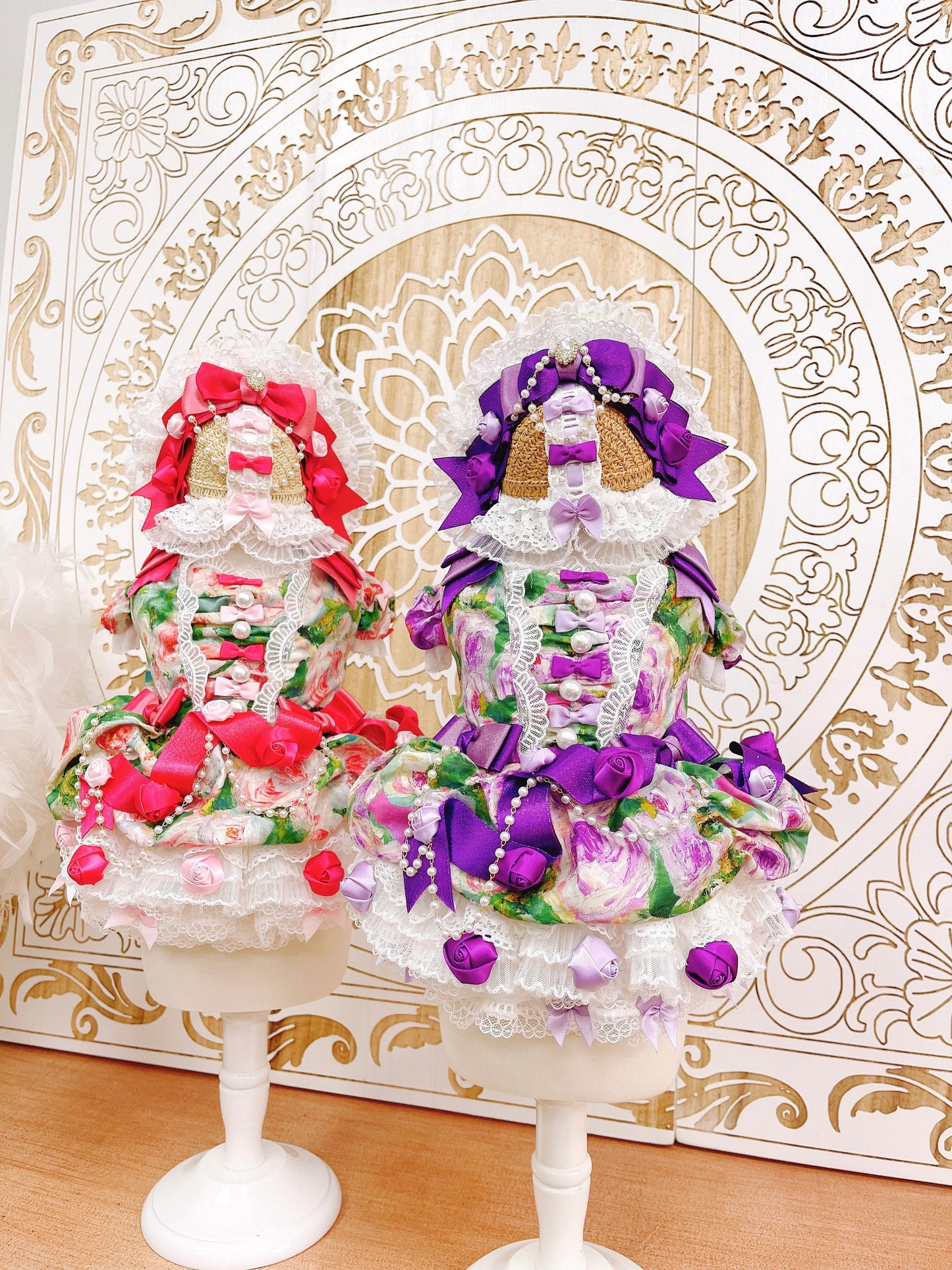 Decorative figurines on stands with colorful flowers against an ornate gold and white background