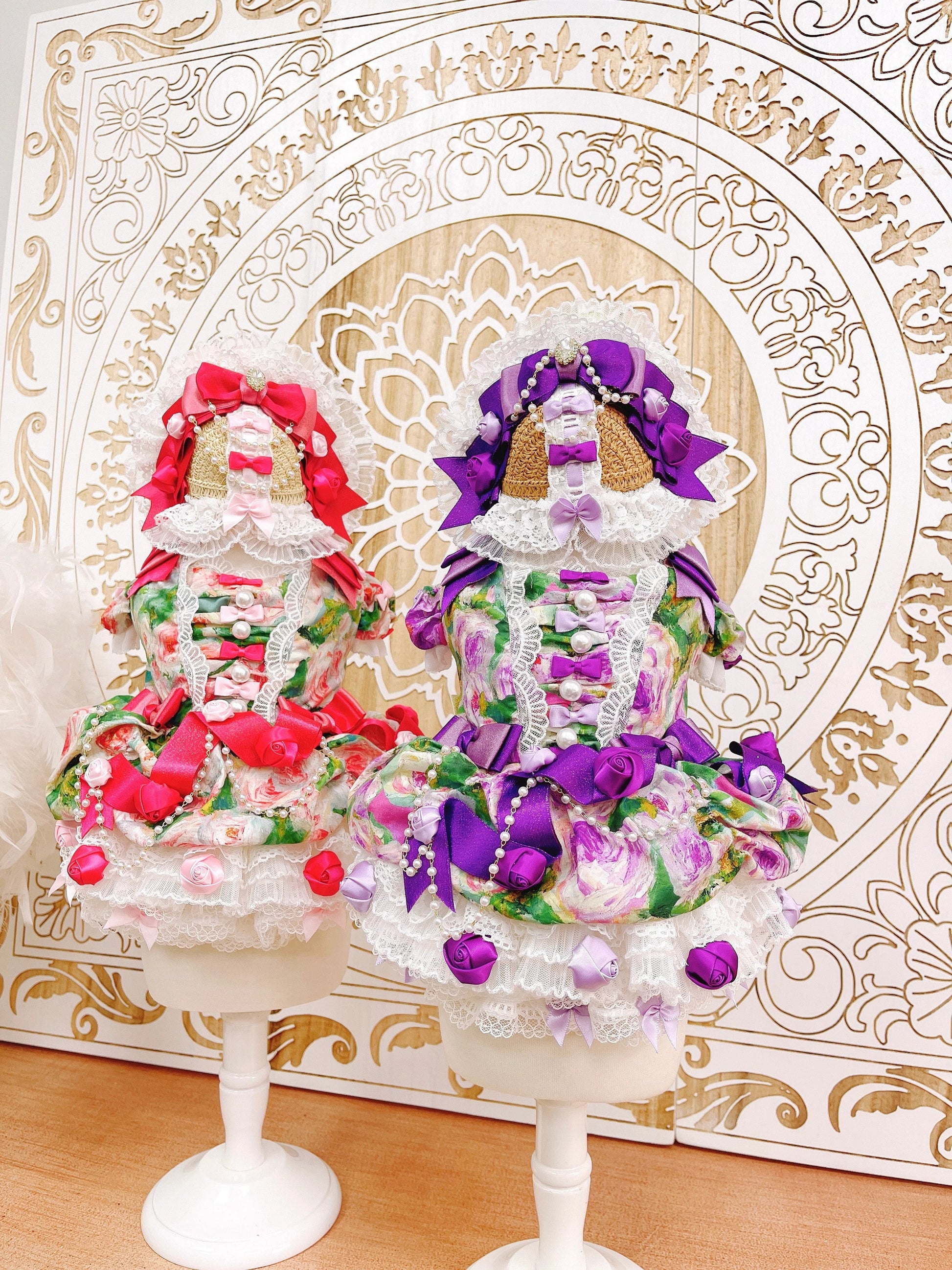 Decorative figurines on stands with colorful flowers against an ornate gold and white background