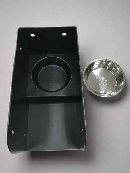 Black plastic component with a silver metal disc on a gray background