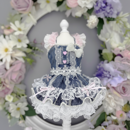 Small doll in a blue dress with lace details against a floral wreath background