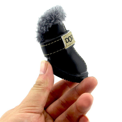 Black dog boot with gray fur on top held in a hand against a white background