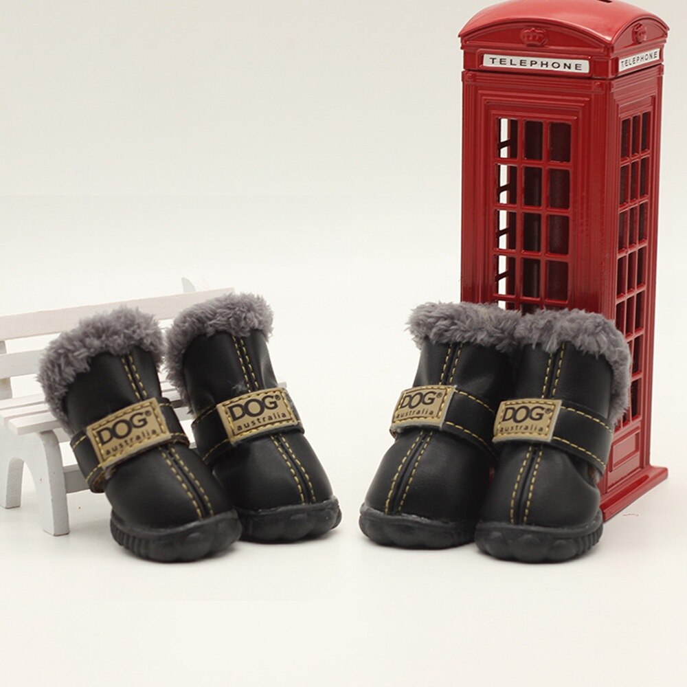 Black dog boots with gray fur lining in front of a red telephone box on a white background