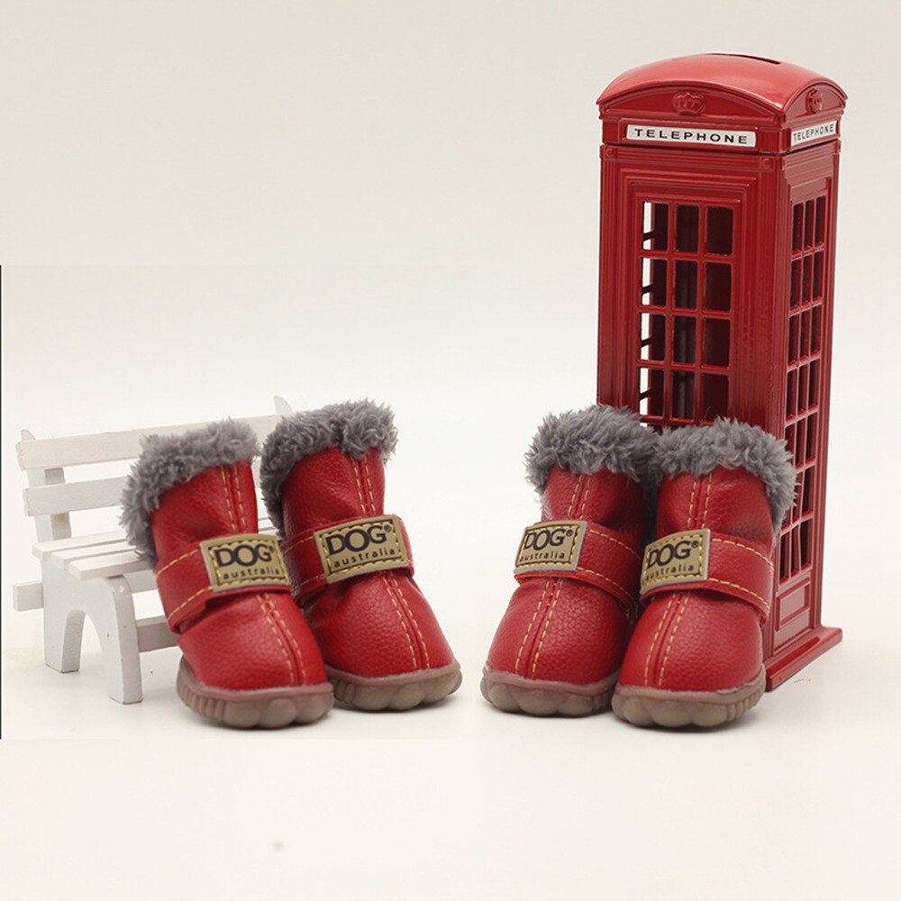 Red dog boots with gray fur lining in front of a miniature red telephone box on a white background