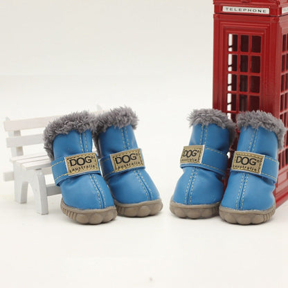 Blue dog boots with gray fur trim and visible brand logo in front of a red telephone box.