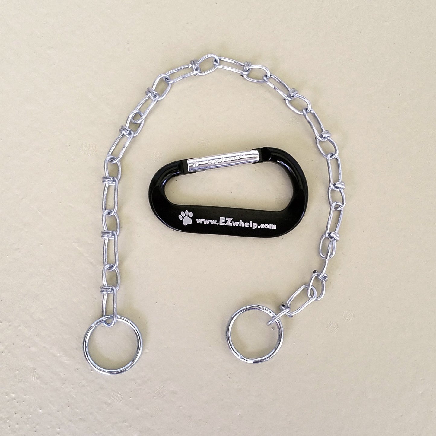 Dog training tool with chain and carabiner on a beige background