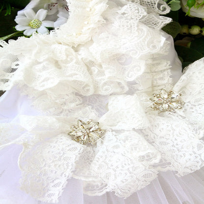 Close-up of a white lace garment with floral details and brooches.