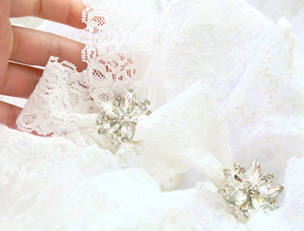 Close-up of white lace fabric with floral embellishments on a white background