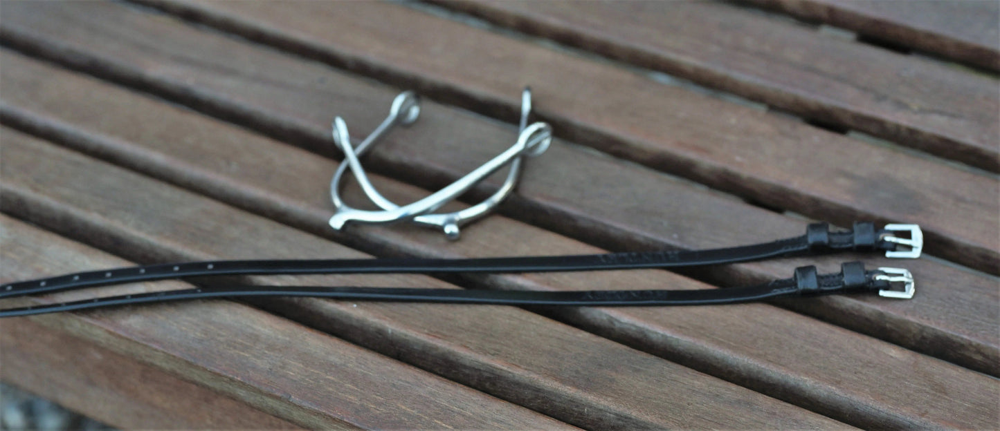 Two black straps with metal buckles on a wooden surface