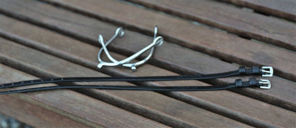 Two black straps with metal buckles on a wooden surface