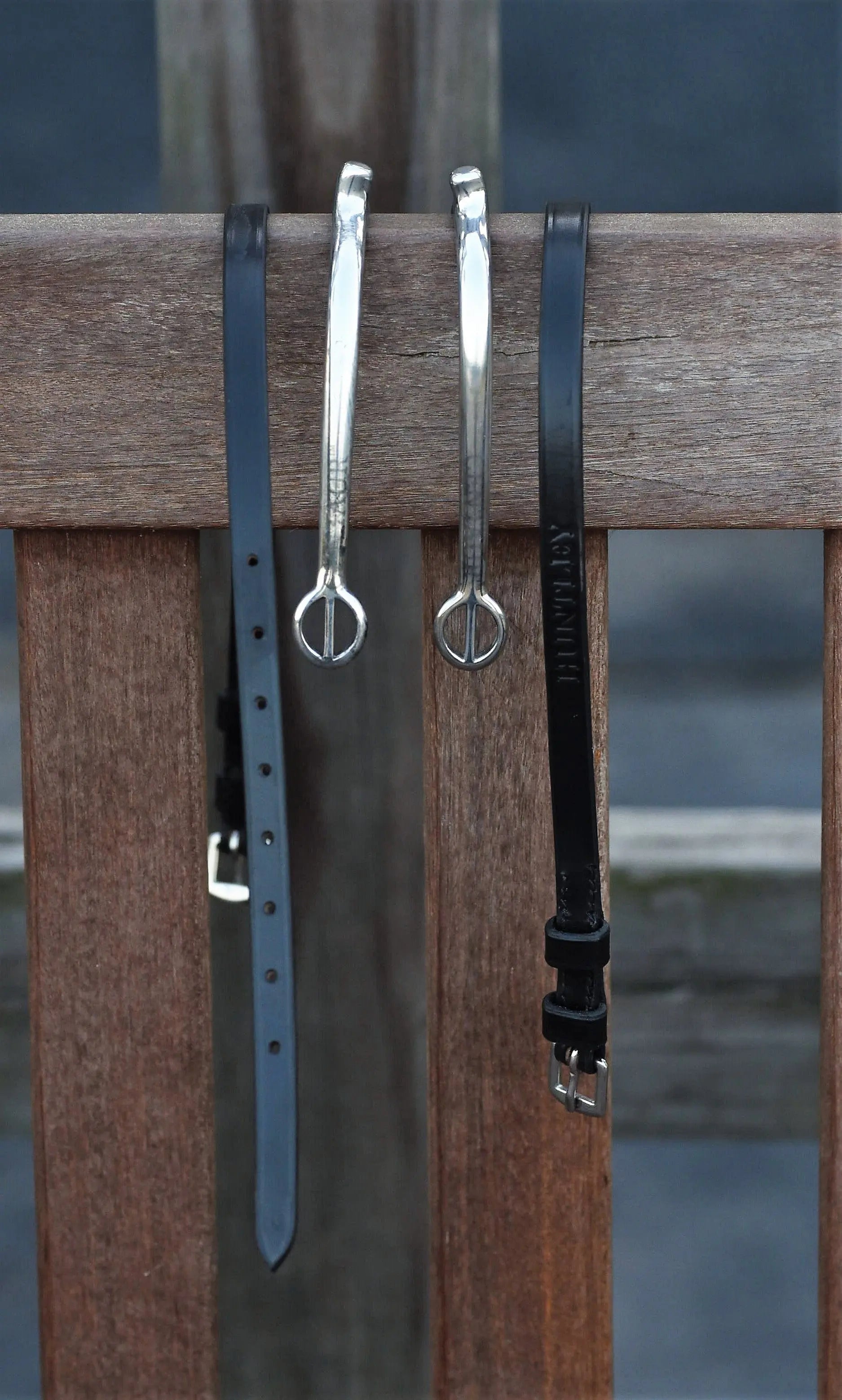 Two silver bracelets with black straps on a wooden surface.