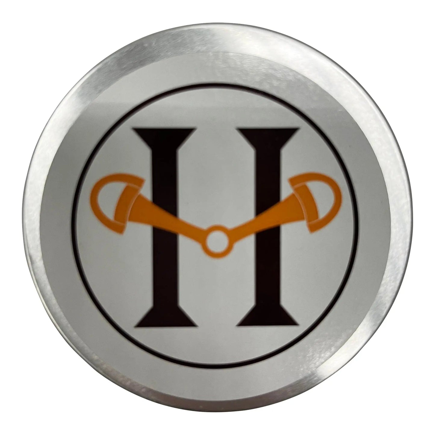 Circular metal badge with a logo featuring a stylized 'H' with orange accents on a white background