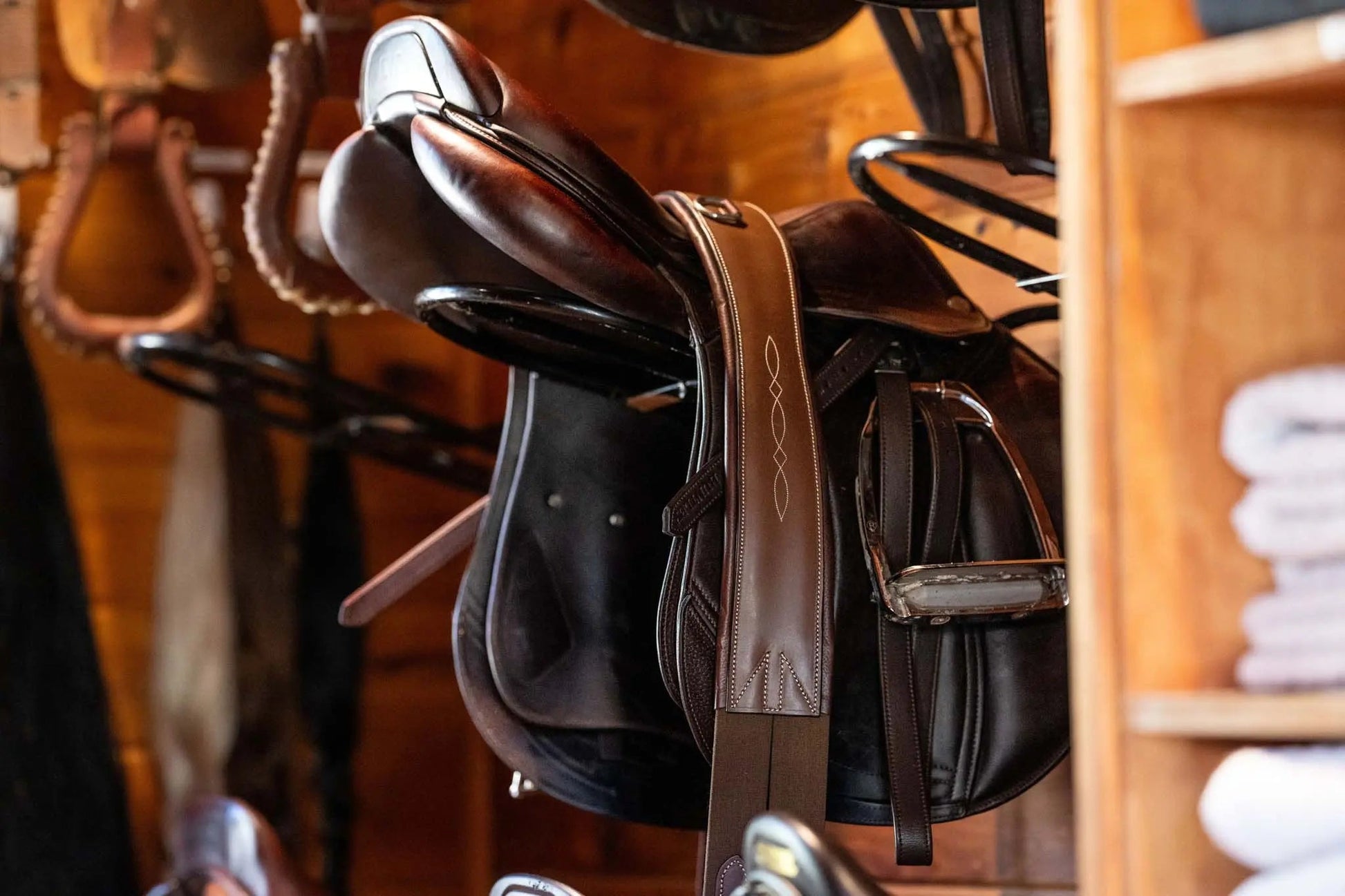 Brown leather saddle on a wooden rack with a blurred background