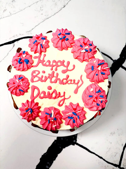 Birthday cake with pink frosting and 'Happy Birthday Daisy' text on a white background