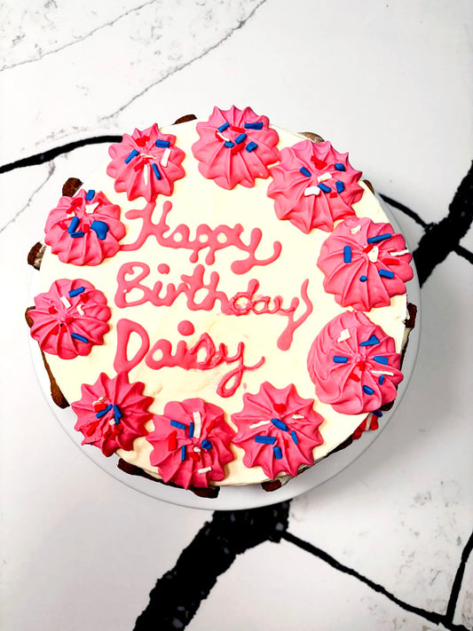 Birthday cake with pink frosting and 'Happy Birthday Daisy' text on a white background