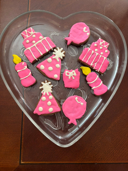 Decorative cookies shaped like birthday items on a heart-shaped tray.