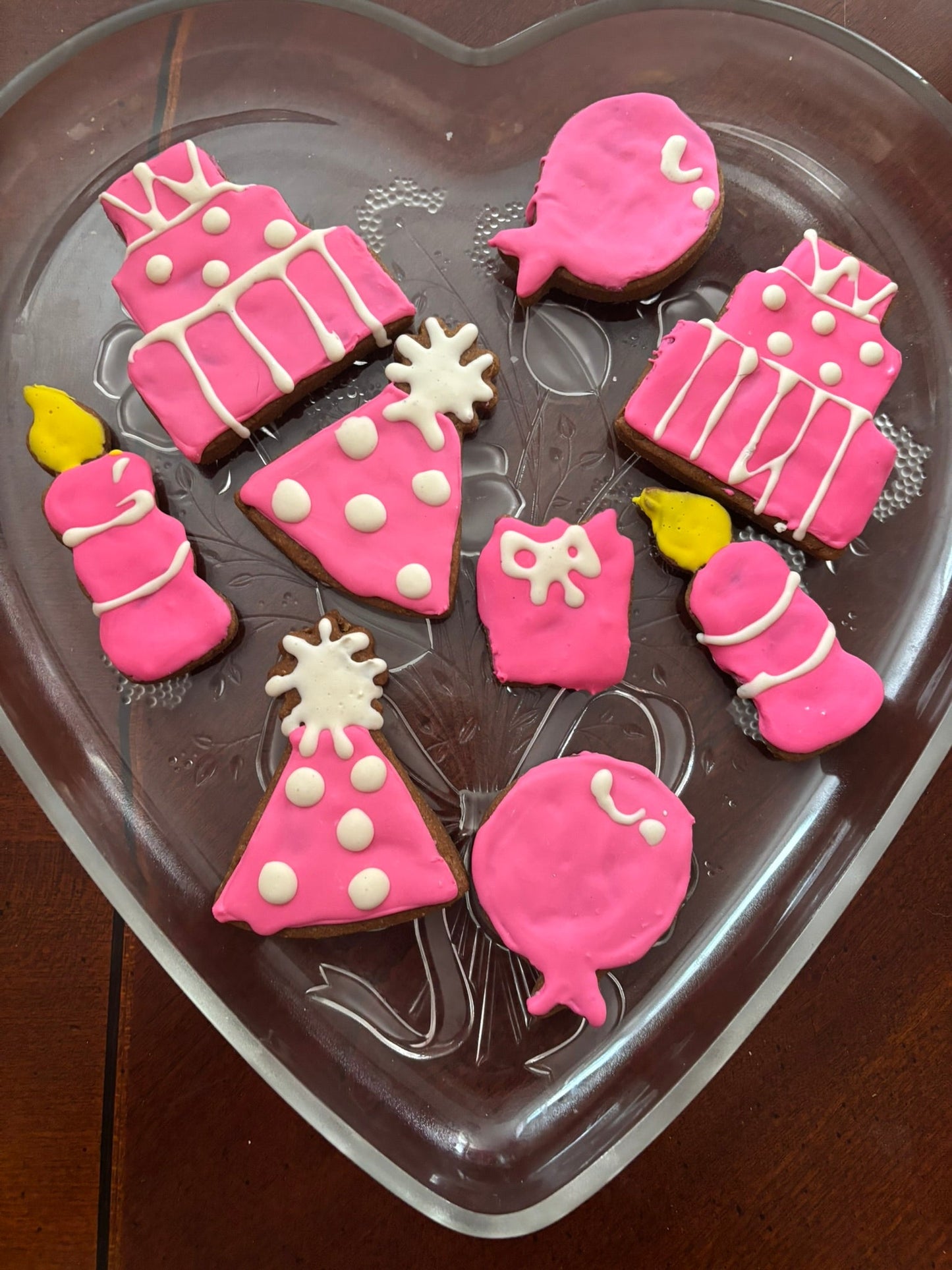 Decorative cookies shaped like baby items on a heart-shaped cookie cutter.