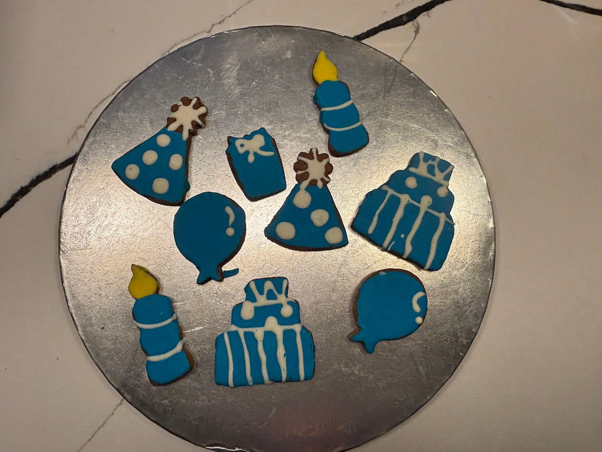 Decorative blue and white cookies shaped like birthday items on a metal tray.