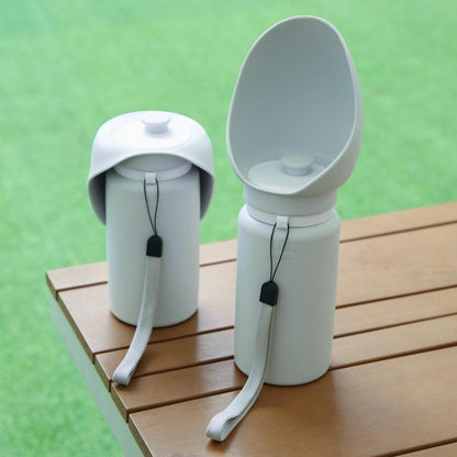 Two white pet travel bowls with lids on a wooden surface against a green background