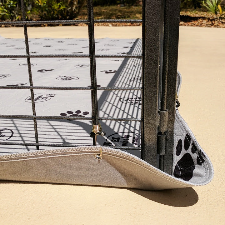 Dog crate with a paw print patterned mat on a sandy ground