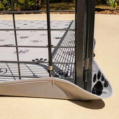 Dog crate with a paw print patterned mat on a sandy ground