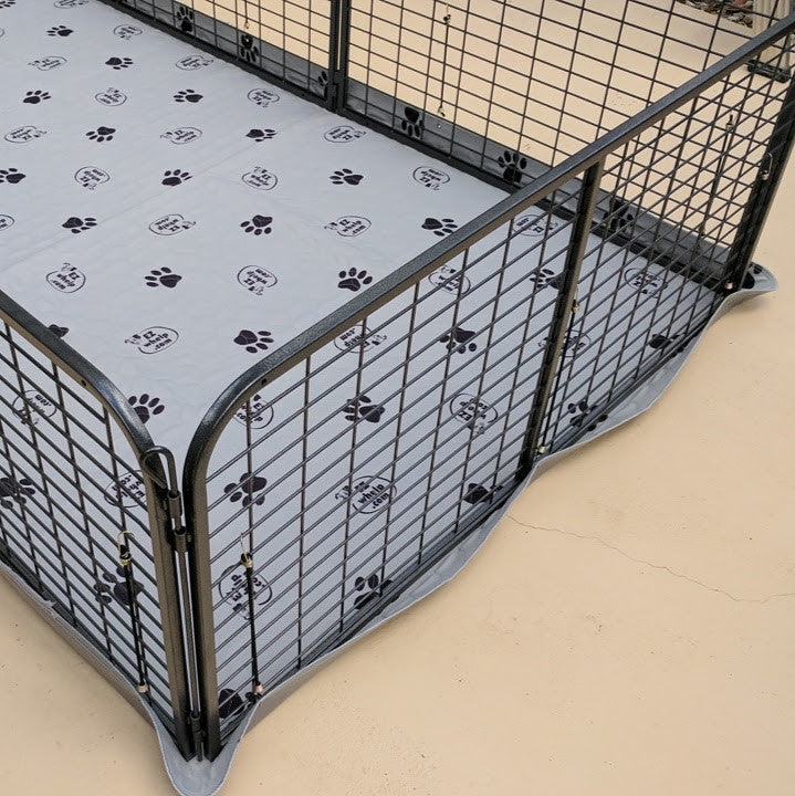 Pet playpen with a gray mat featuring black paw prints on a beige floor.