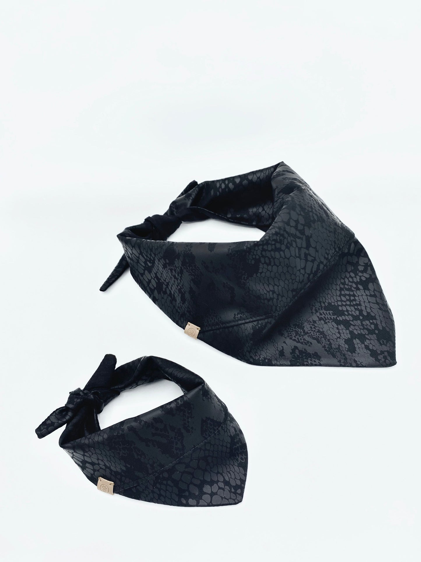 Two black patterned bandanas on a white background