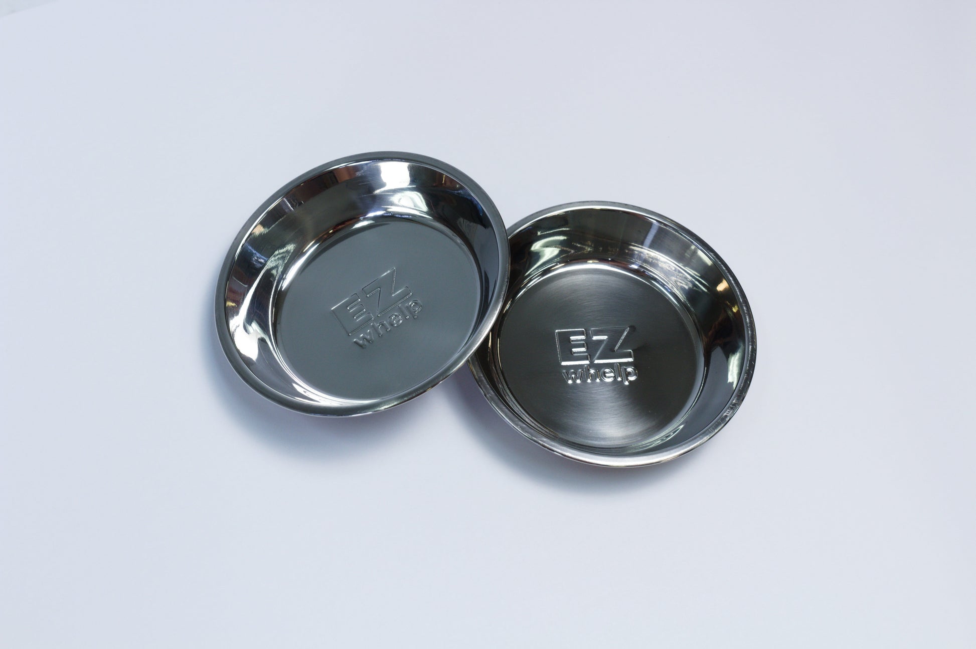 Two metallic bowls with a brand logo on a light gray background