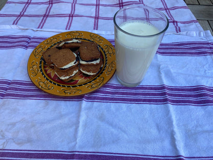 Cookies on a plate with a glass of milk on a striped tablecloth