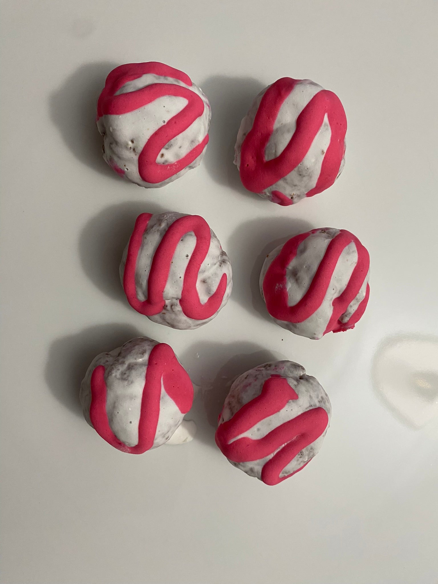 Six spherical treats with pink and gray patterns on a white surface