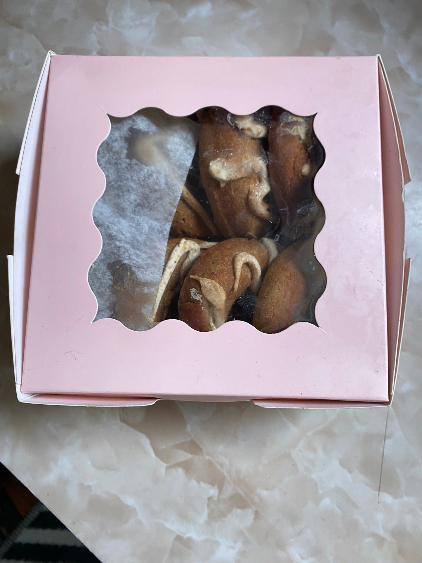 Pink box with a window containing pastries on a marble surface