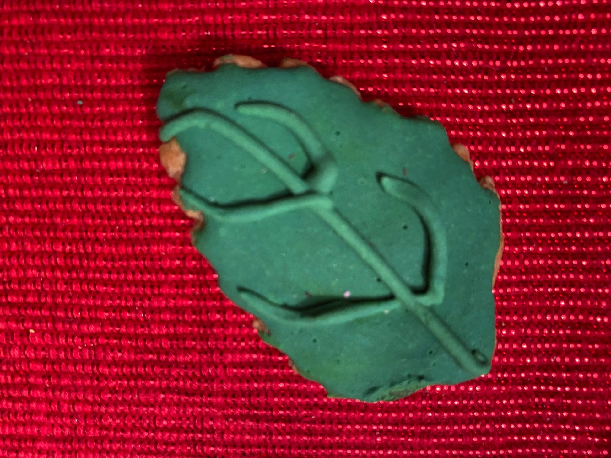 Green plastic object on a red textured background