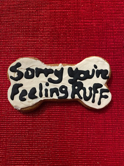 Dog bone-shaped cookie with 'Sorry your feeling ruff' text on a red background