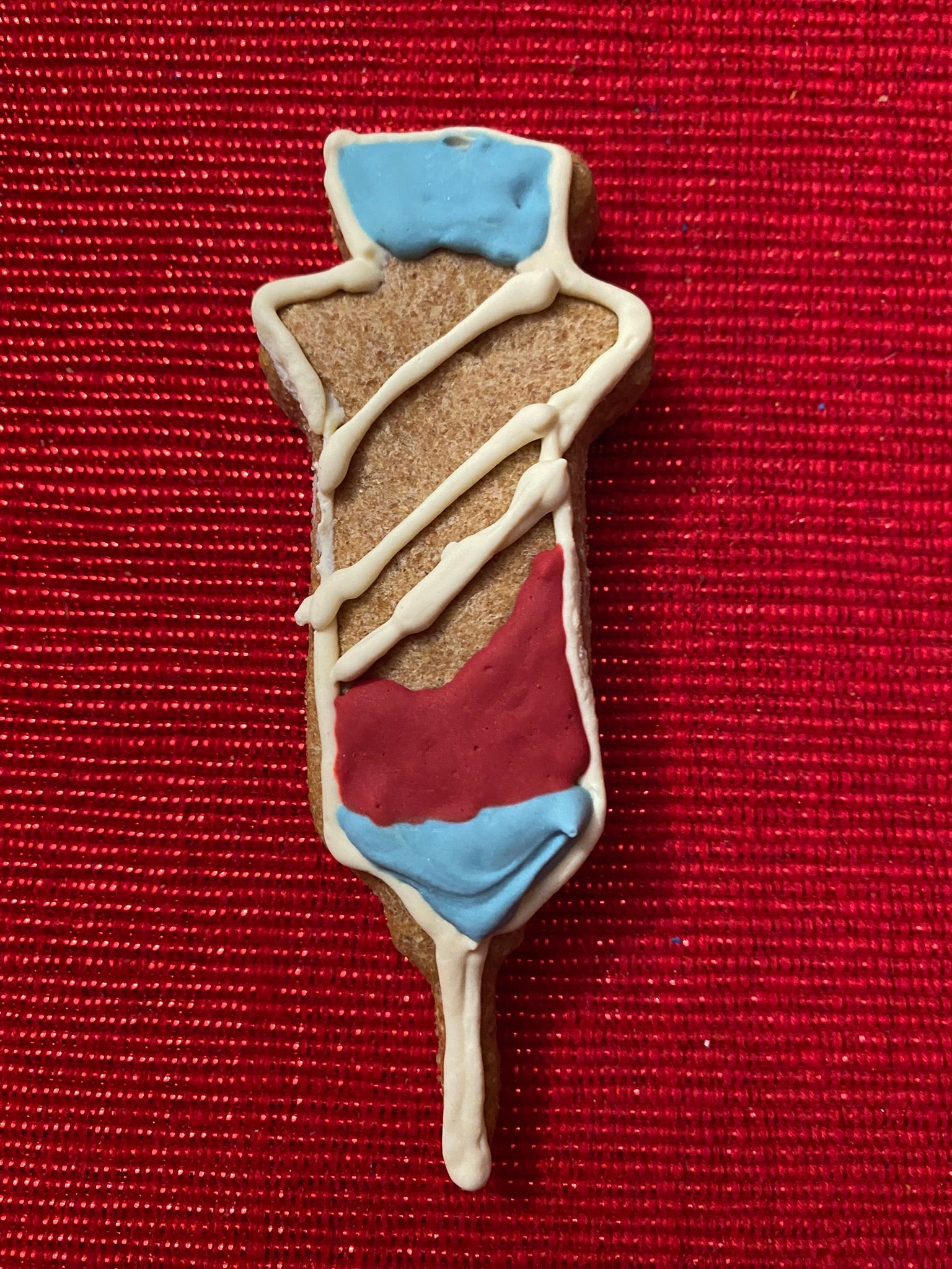 Decorative cookie shaped like a person with blue, red, and beige colors on a red background