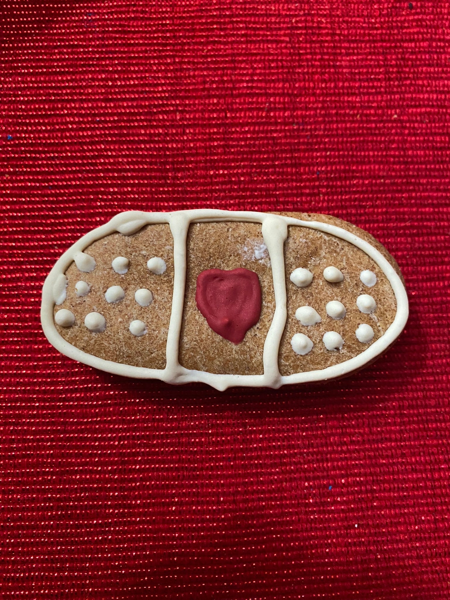 Gingerbread bandaid cookie with a red heart on a red background