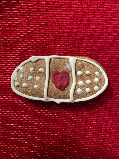 Gingerbread bandaid cookie with a red heart on a red background